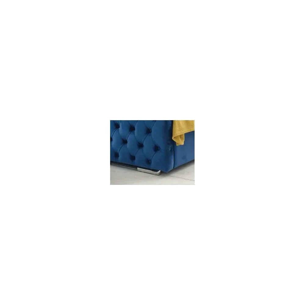 Blue velvet ottoman bed corner with button tufting and chrome feet on white floor