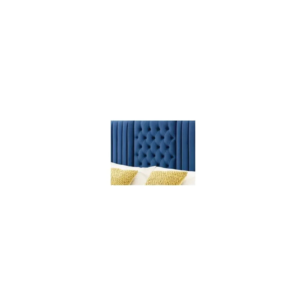 Blue velvet tufted headboard with vertical panels and pillows on bed