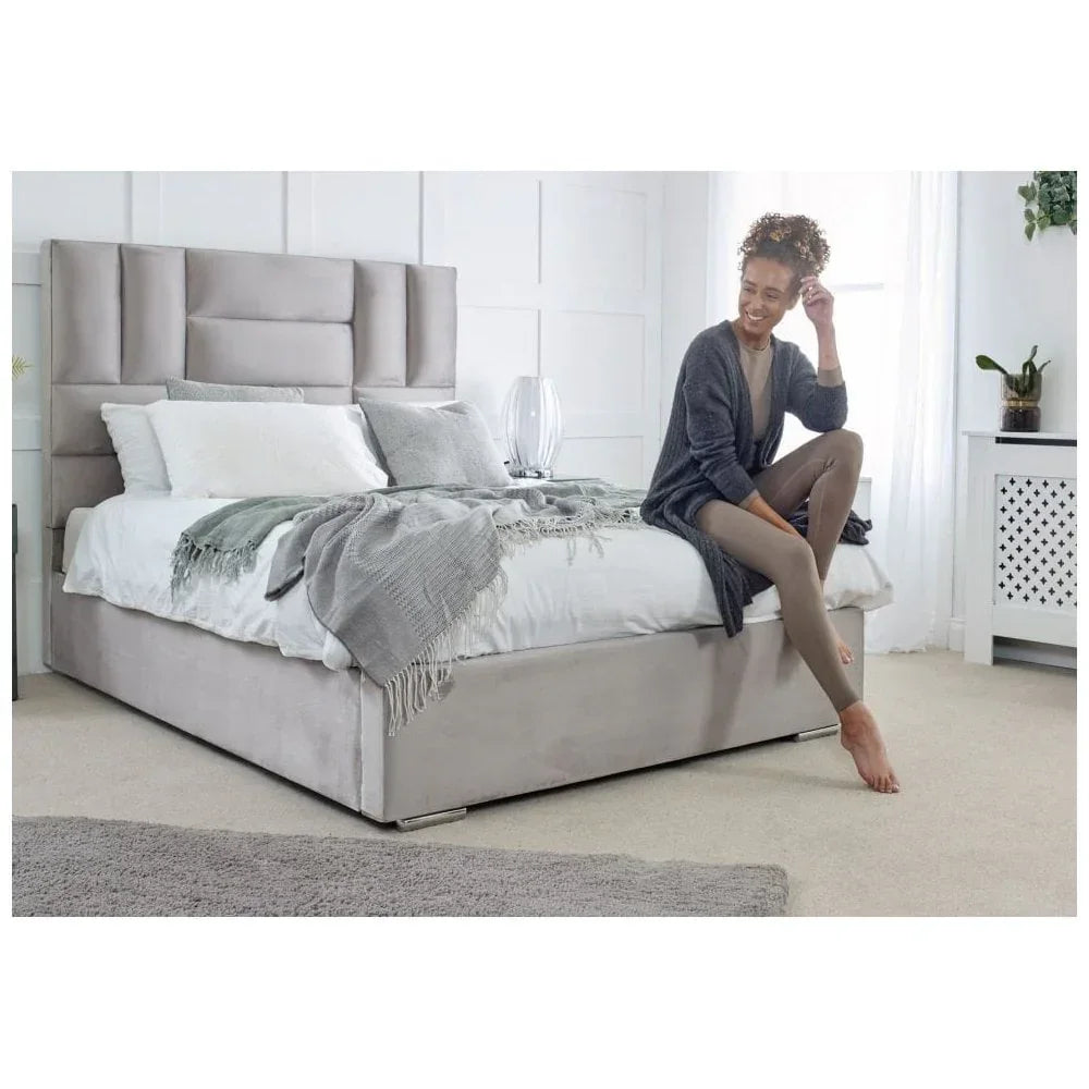 Beige upholstered bed with tall headboard, grey throw, and pillows in bright bedroom