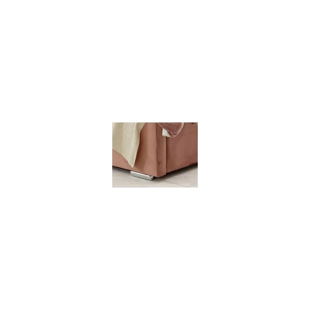 Corner view of blush velvet sofa with chrome leg on tiled floor