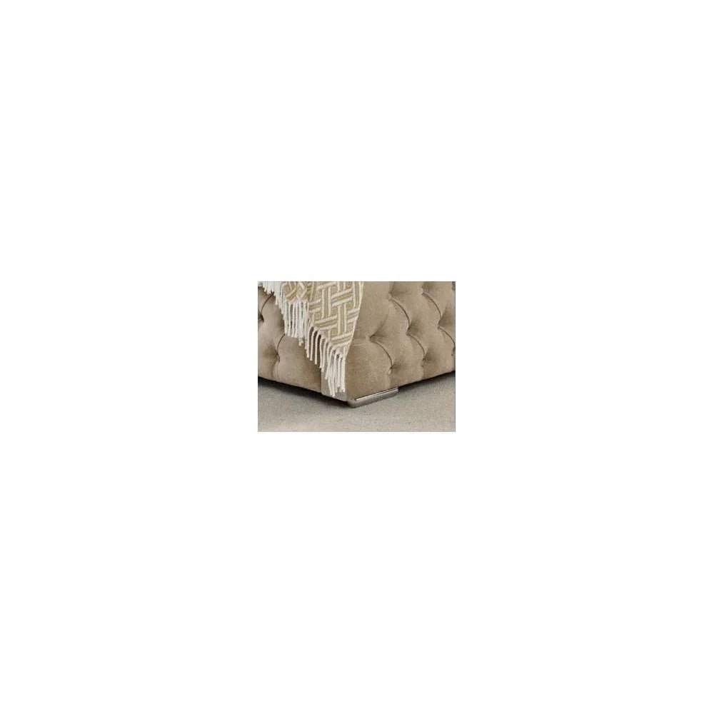 Beige velvet tufted sofa corner with silver legs and patterned throw blanket