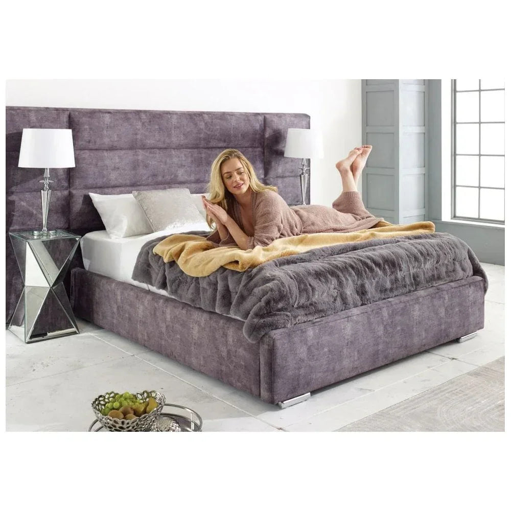 Plush grey upholstered bed with tall headboard, matching throw, and mirrored bedside tables