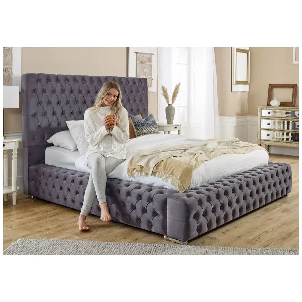 Grey upholstered bed frame with button tufting in a modern bedroom, woman sitting on edge
