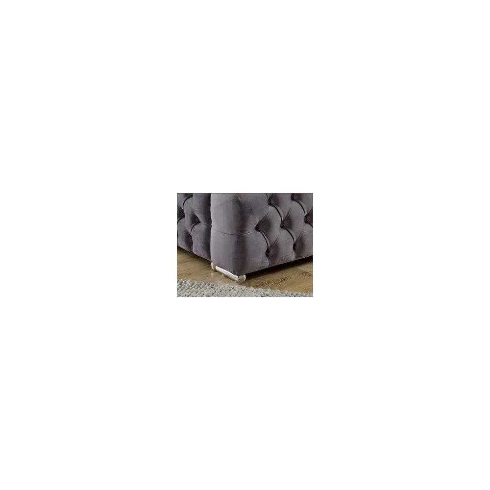 Grey velvet sofa corner with tufted upholstery and chrome leg on wooden floor