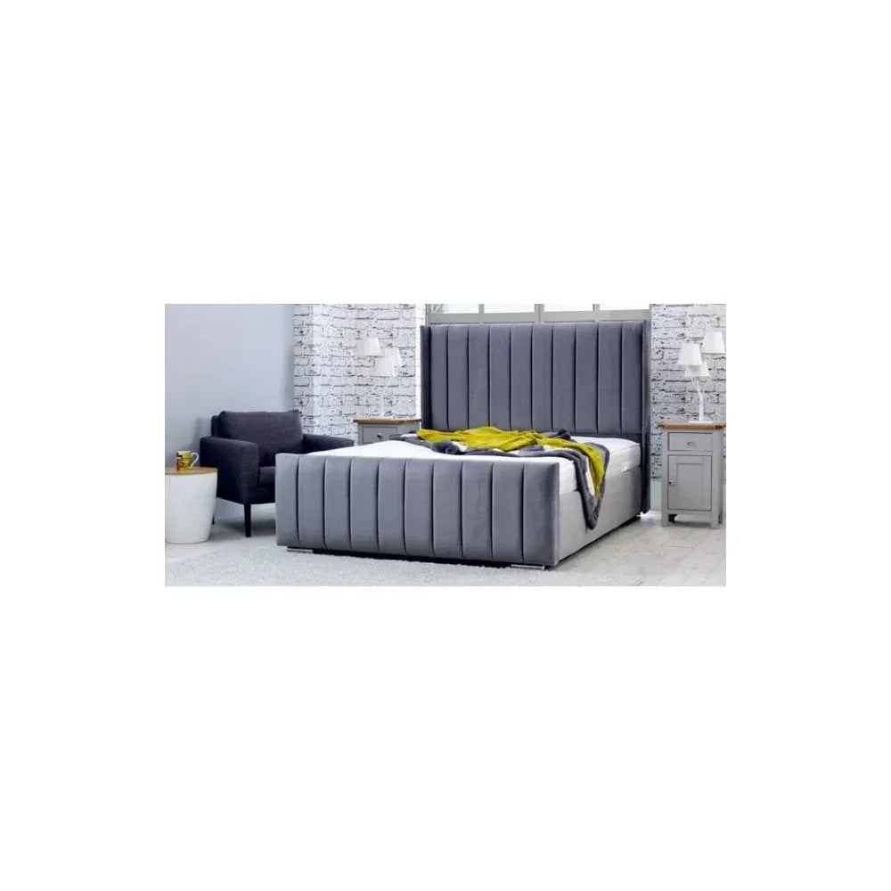 Grey upholstered bed frame with tall headboard, modern chair and bedside tables