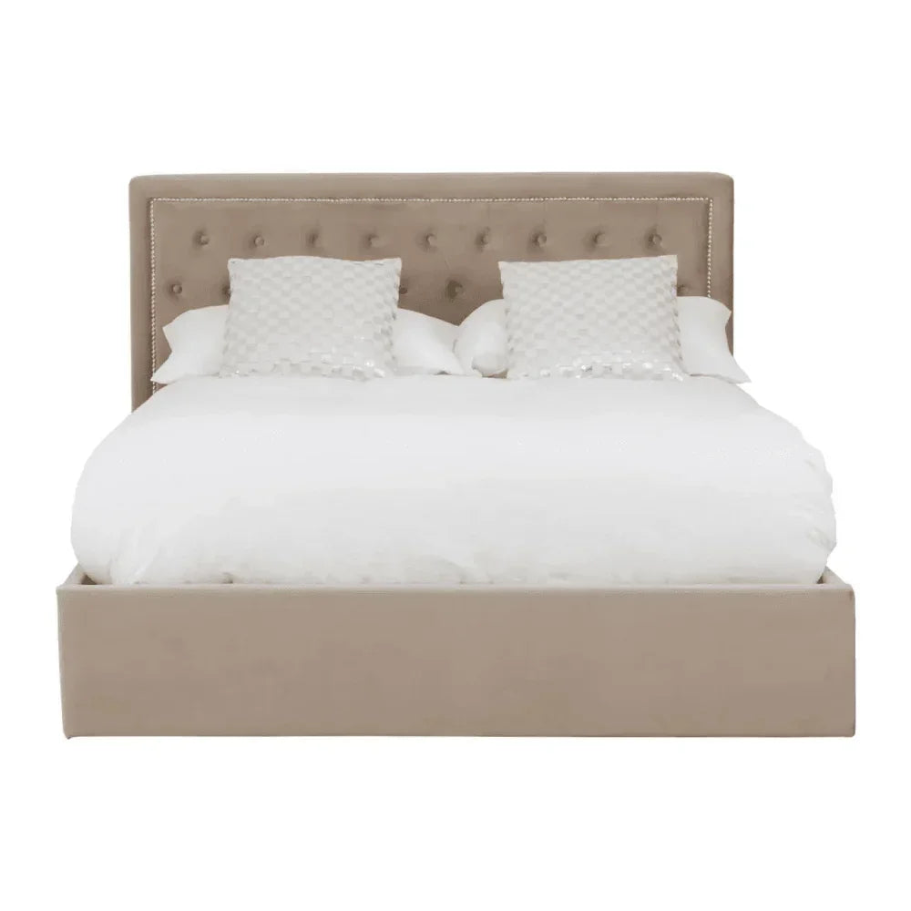 Beige upholstered bed with cushioned headboard, white bedding, and two patterned pillows