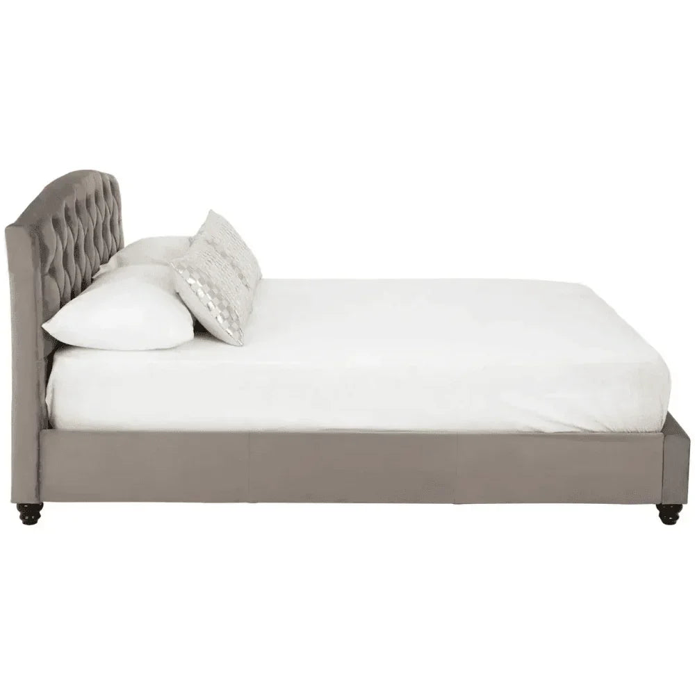 Side view of grey upholstered bed frame with tufted headboard and white bedding