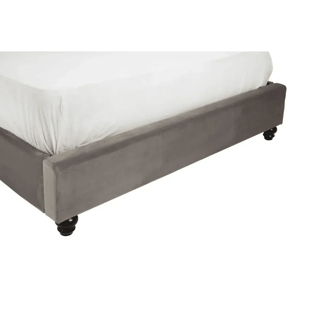 Grey upholstered bed base with turned wooden legs, side angle view