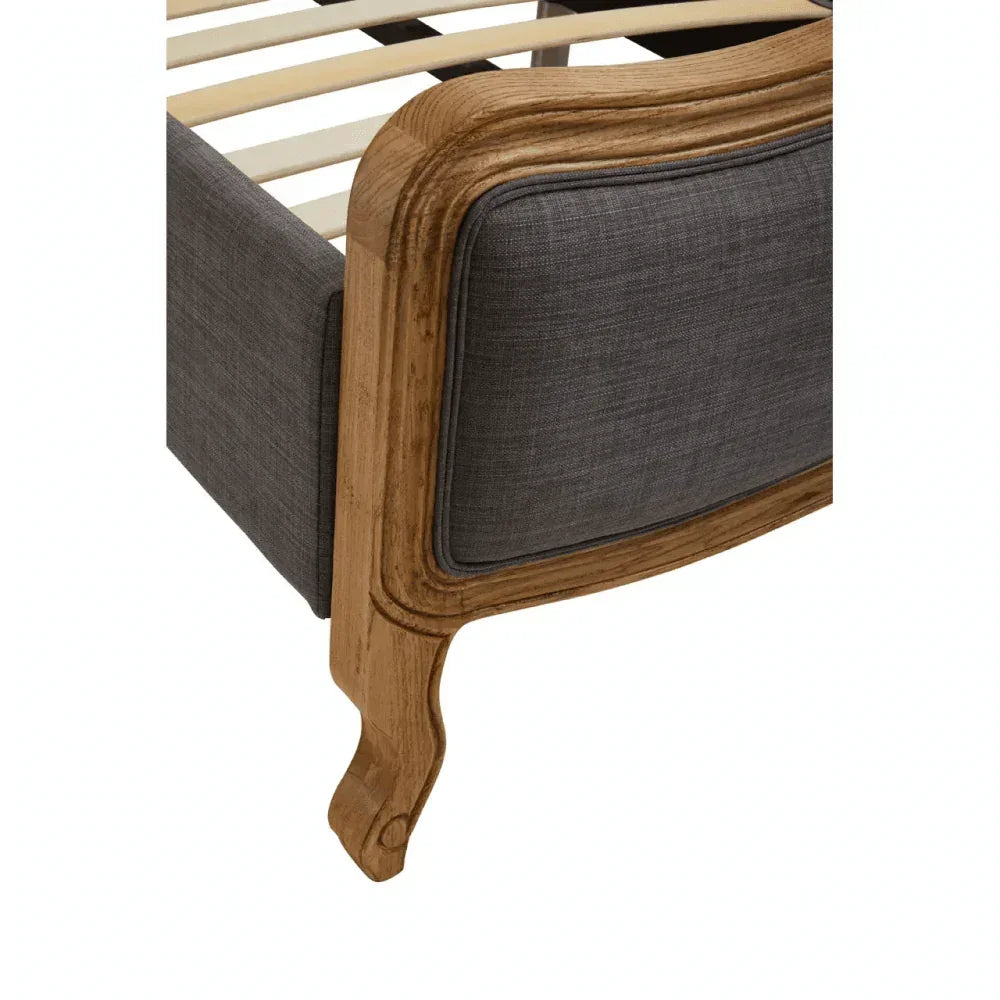 Oak bed frame corner with grey upholstered panel and visible wooden leg detail