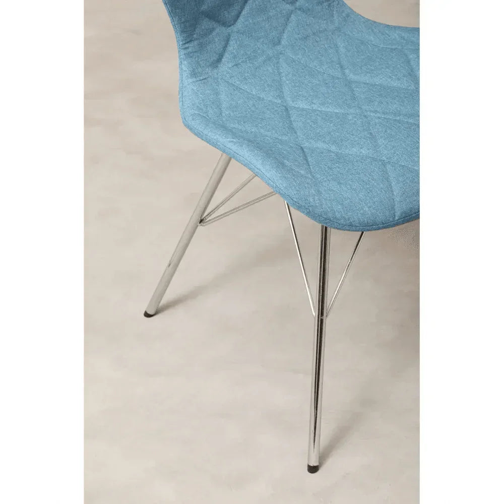 Blue fabric dining chair with chrome legs and quilted seat detail on light floor