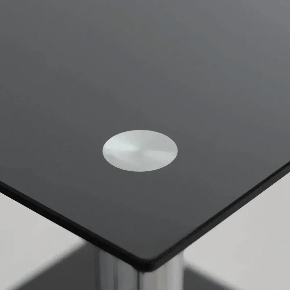 Closeup of black glass coffee table corner with metal accent and chrome legs