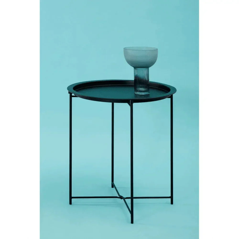 Black metal round side table with glass on top against blue background