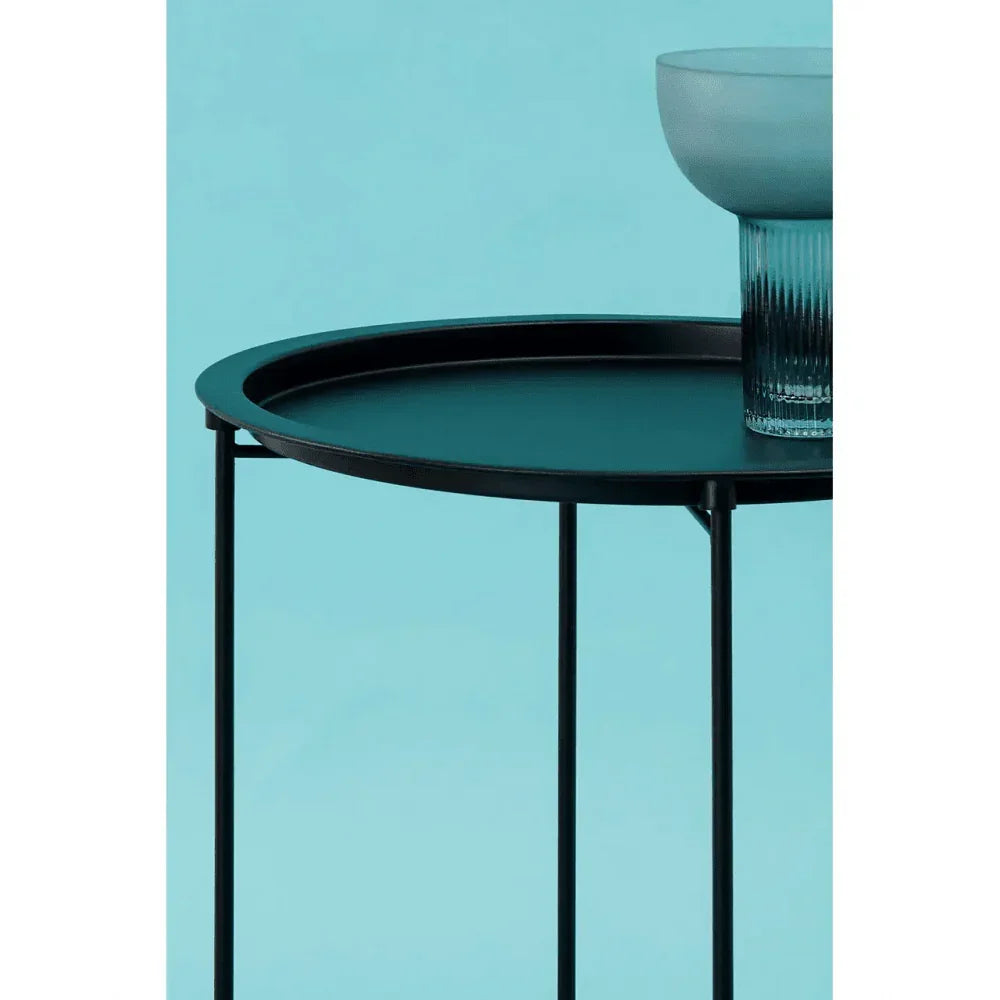 Black metal round side table with thin legs and glass bowl on blue background