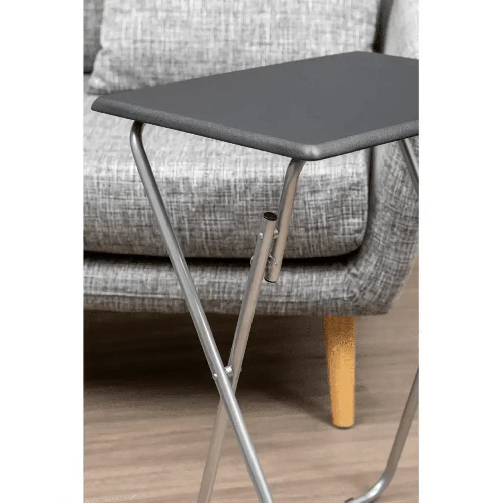 Black folding tray table with metal legs beside grey fabric sofa on wooden floor