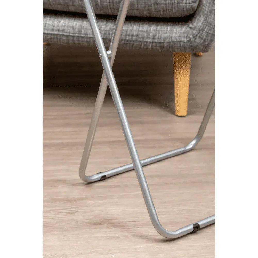 Metal folding table legs on laminate floor beside grey upholstered sofa