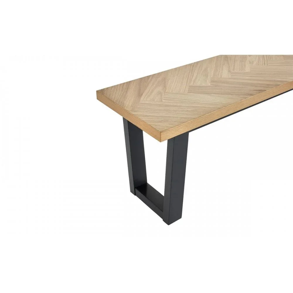 Rectangular dining table with herringbone wood top and black metal legs, angled view