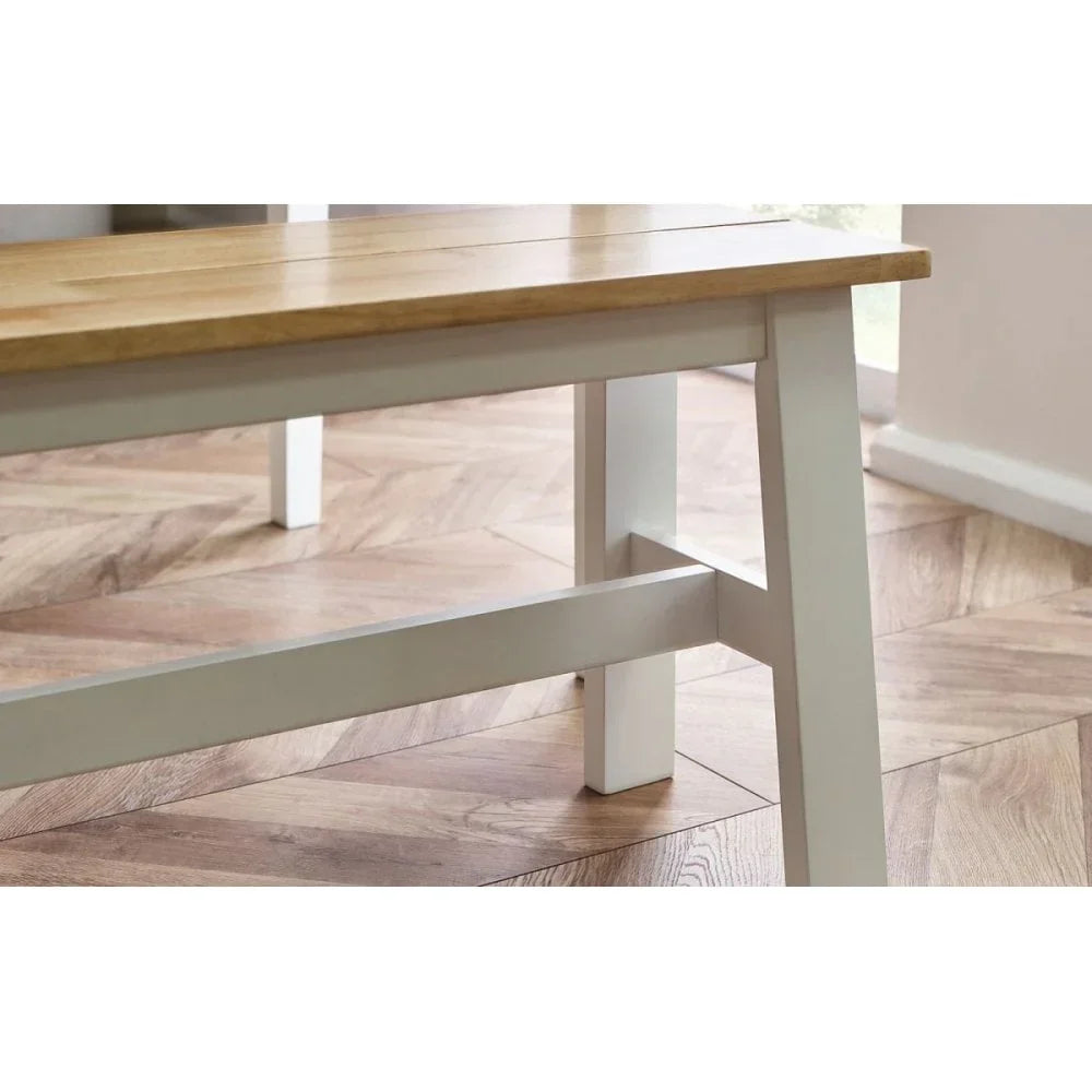 Wooden dining bench with white painted legs on chevron parquet floor