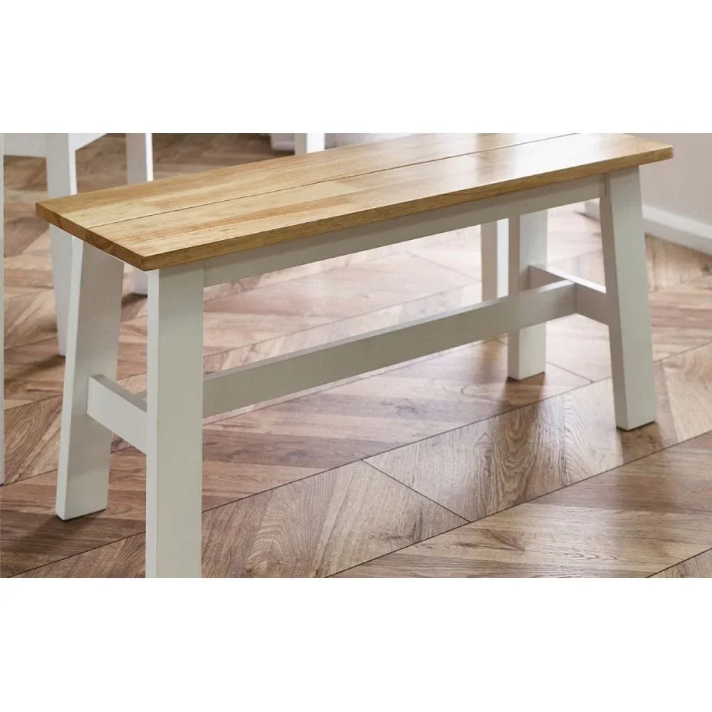 Wooden dining bench with white legs and natural oak seat on herringbone floor