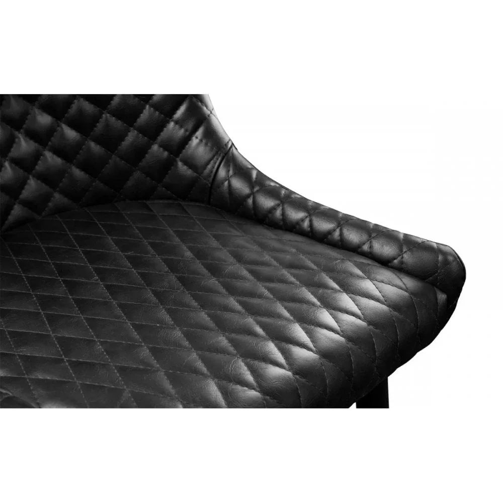 Closeup of black quilted leather dining chair seat with curved armrest