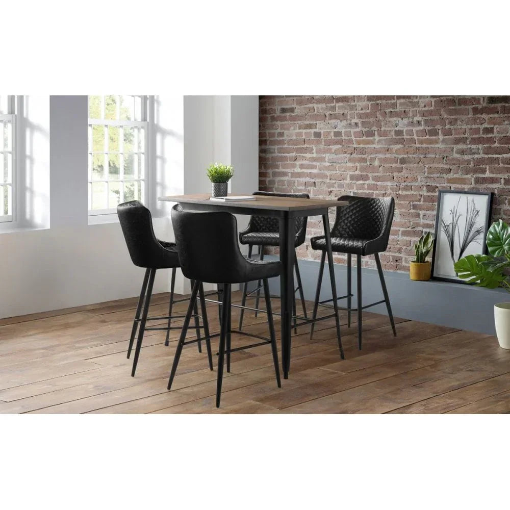 Black bar stools with quilted seats around a wooden high table in modern dining area