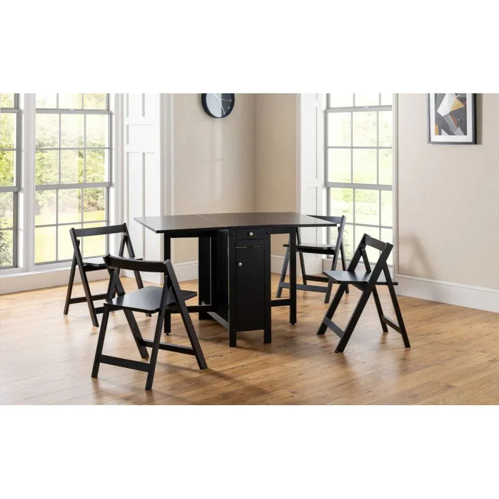 Black folding dining table with four matching folding chairs in bright dining room