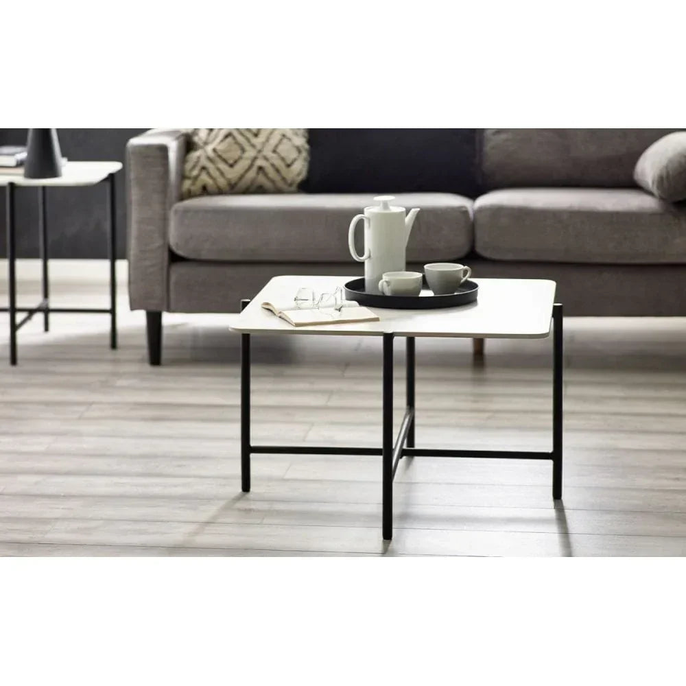 Modern coffee table with white top and black metal legs set in front of grey sofa