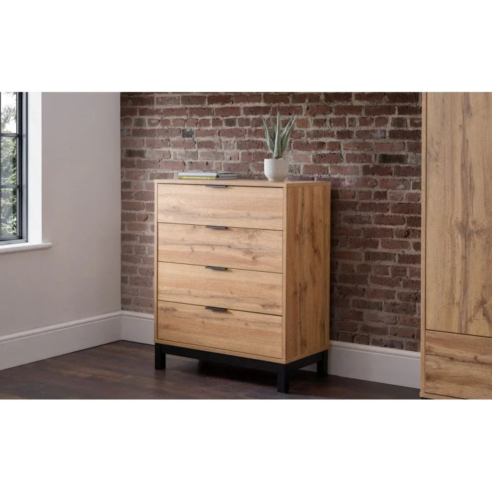 Oak chest of drawers with black metal legs against brick wall in modern bedroom