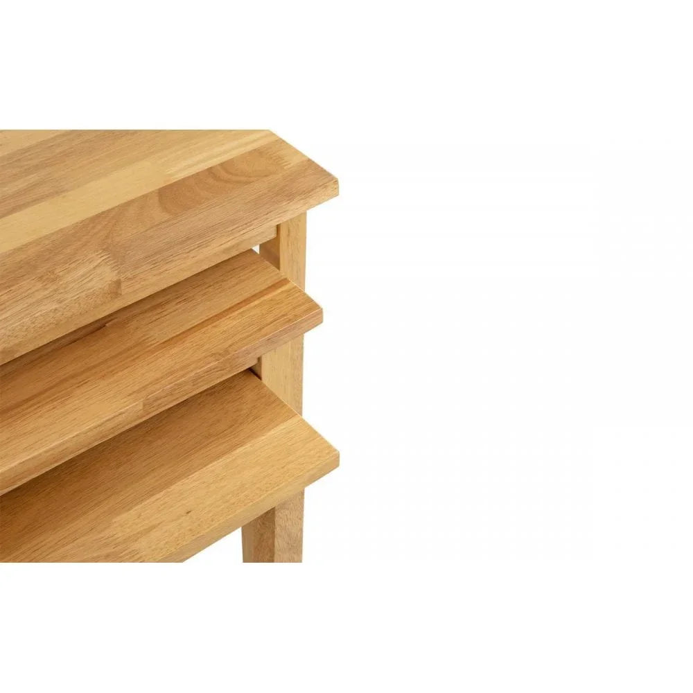 Set of three nested oak tables with smooth wood grain, close-up corner view