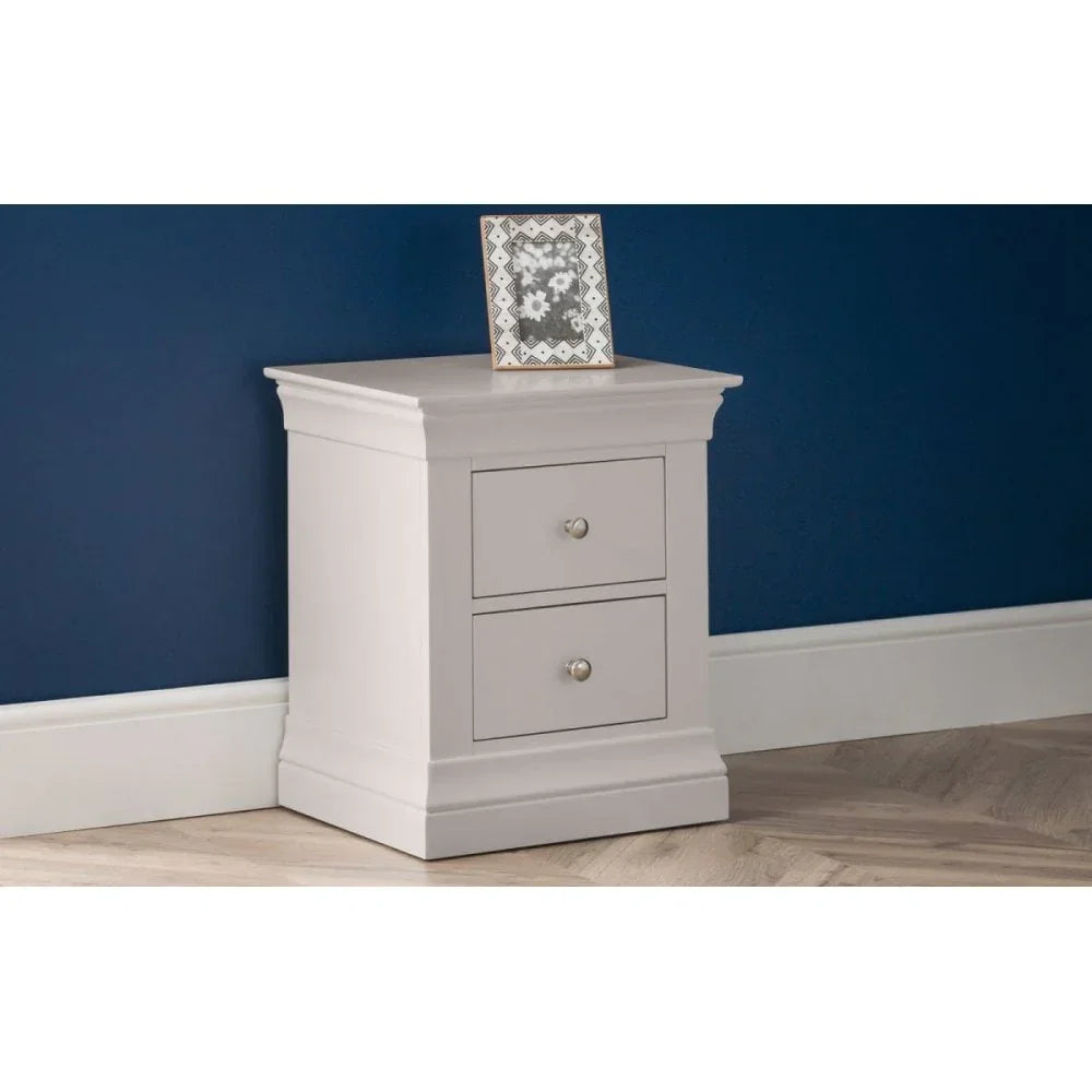 Grey bedside table with two drawers and metal handles against blue wall