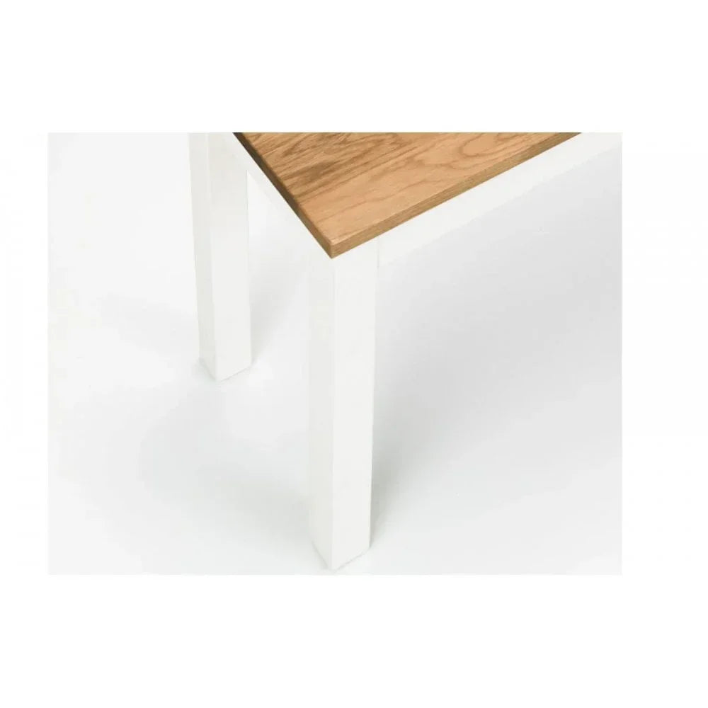 Closeup of wooden dining table corner with white legs and oak finish top