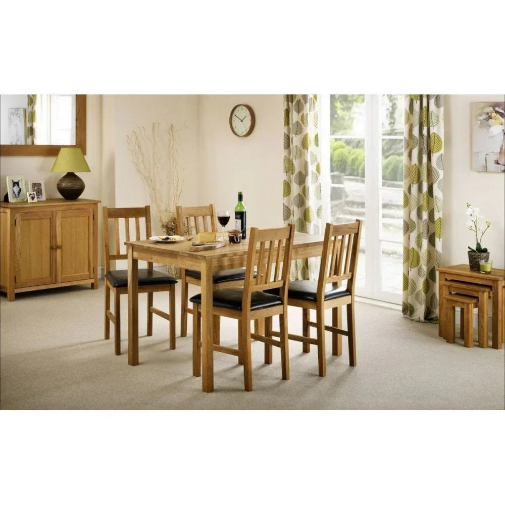 Oak dining table set with four chairs upholstered in black, shown in a modern dining room
