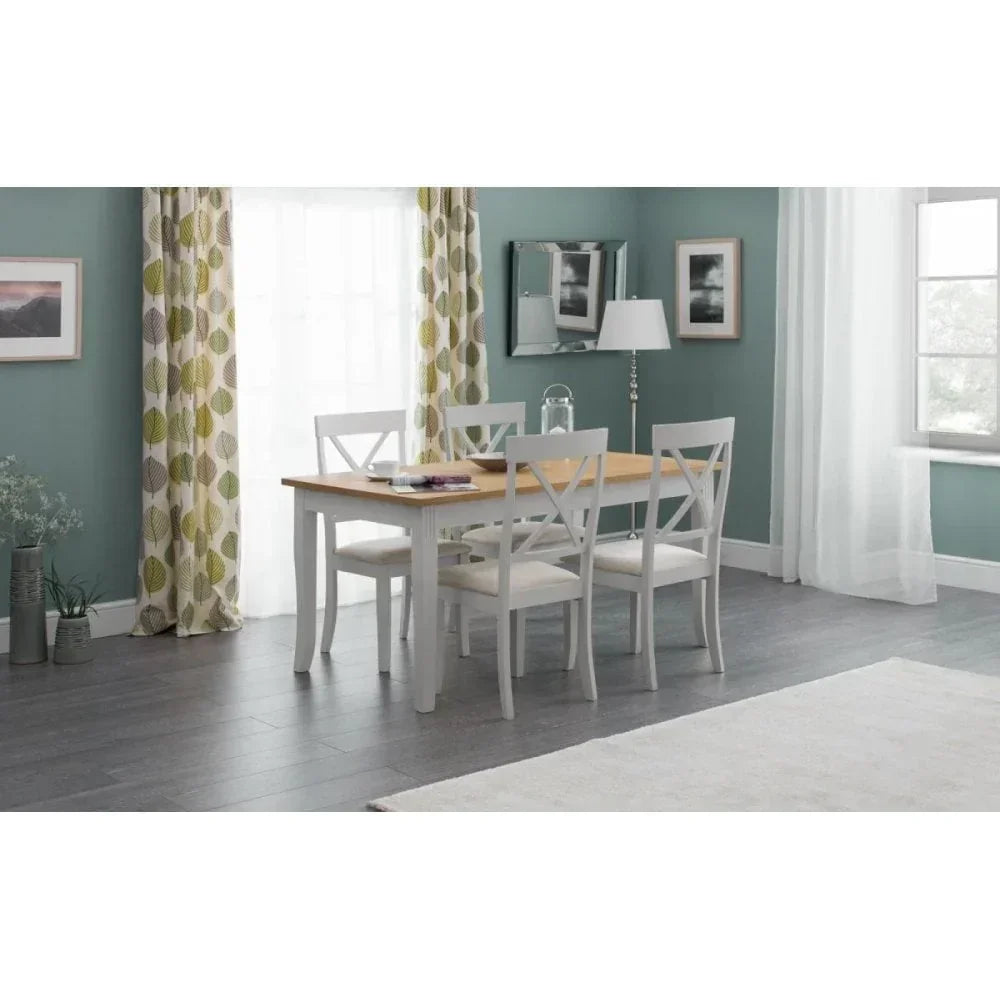 Modern dining table with four white chairs in a bright room with green patterned curtains