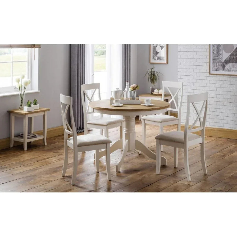 Round wooden dining table with four white chairs in a bright dining room