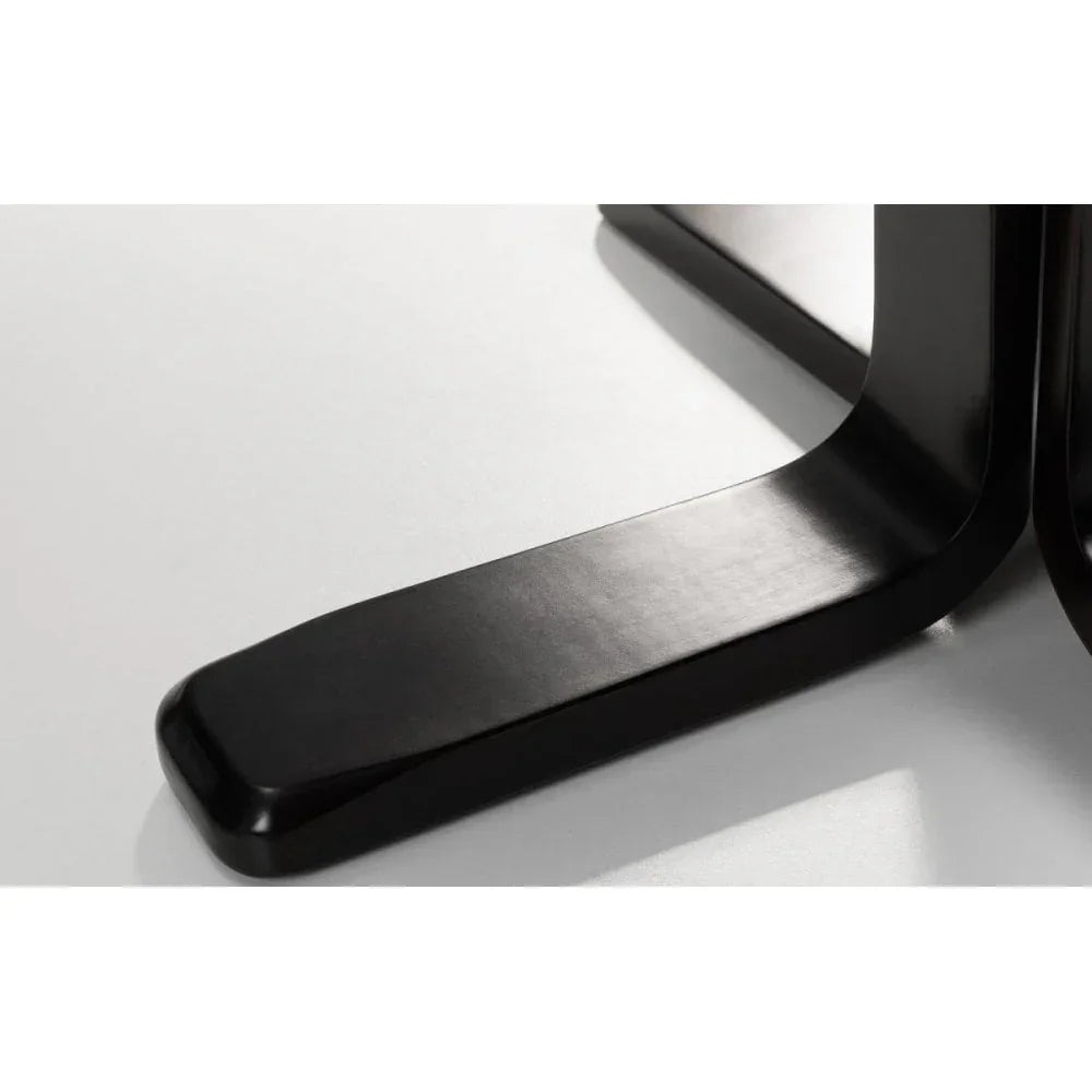 Black metal table base with curved legs on white floor