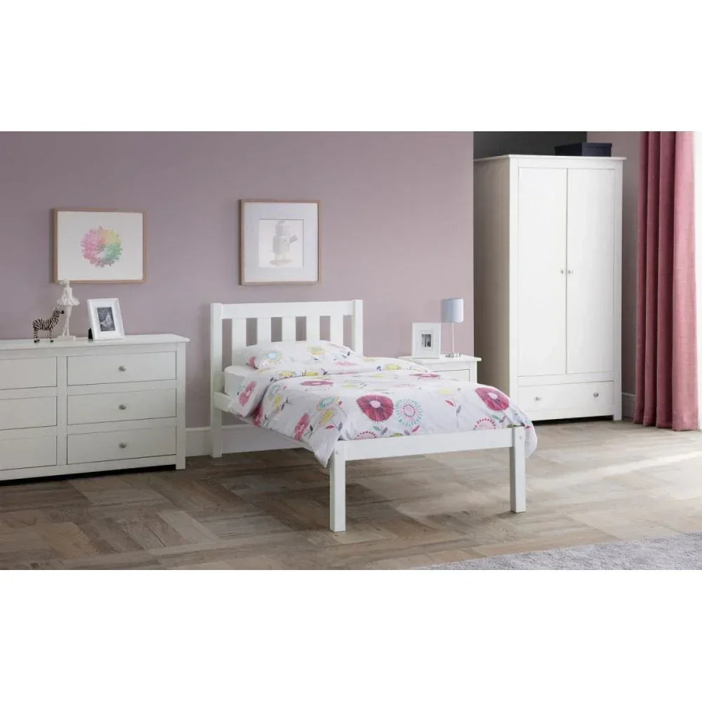 White wooden single bed with floral bedding beside matching wardrobe and dresser in bedroom