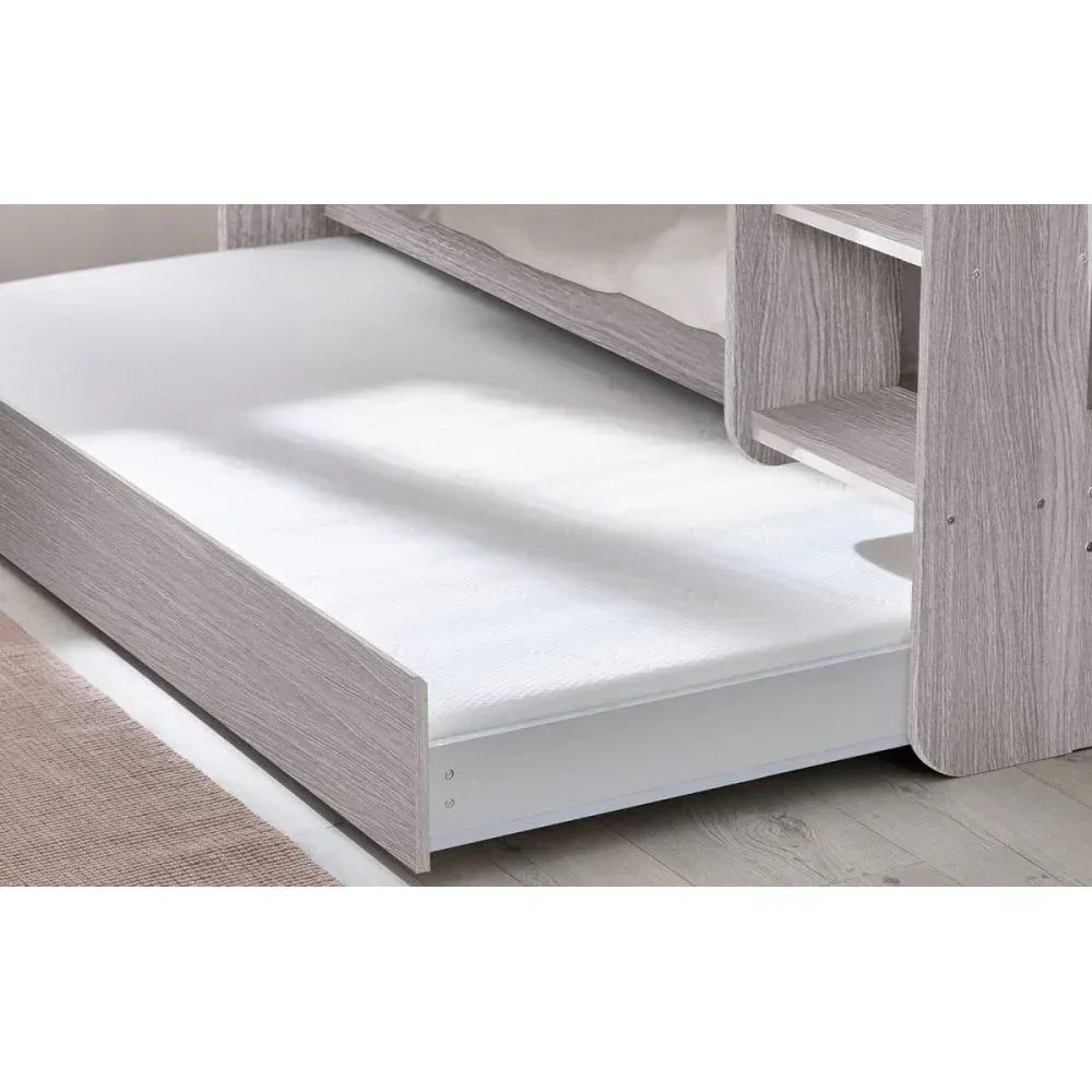 Light wood finish underbed trundle with white mattress beside bunk bed on wooden floor