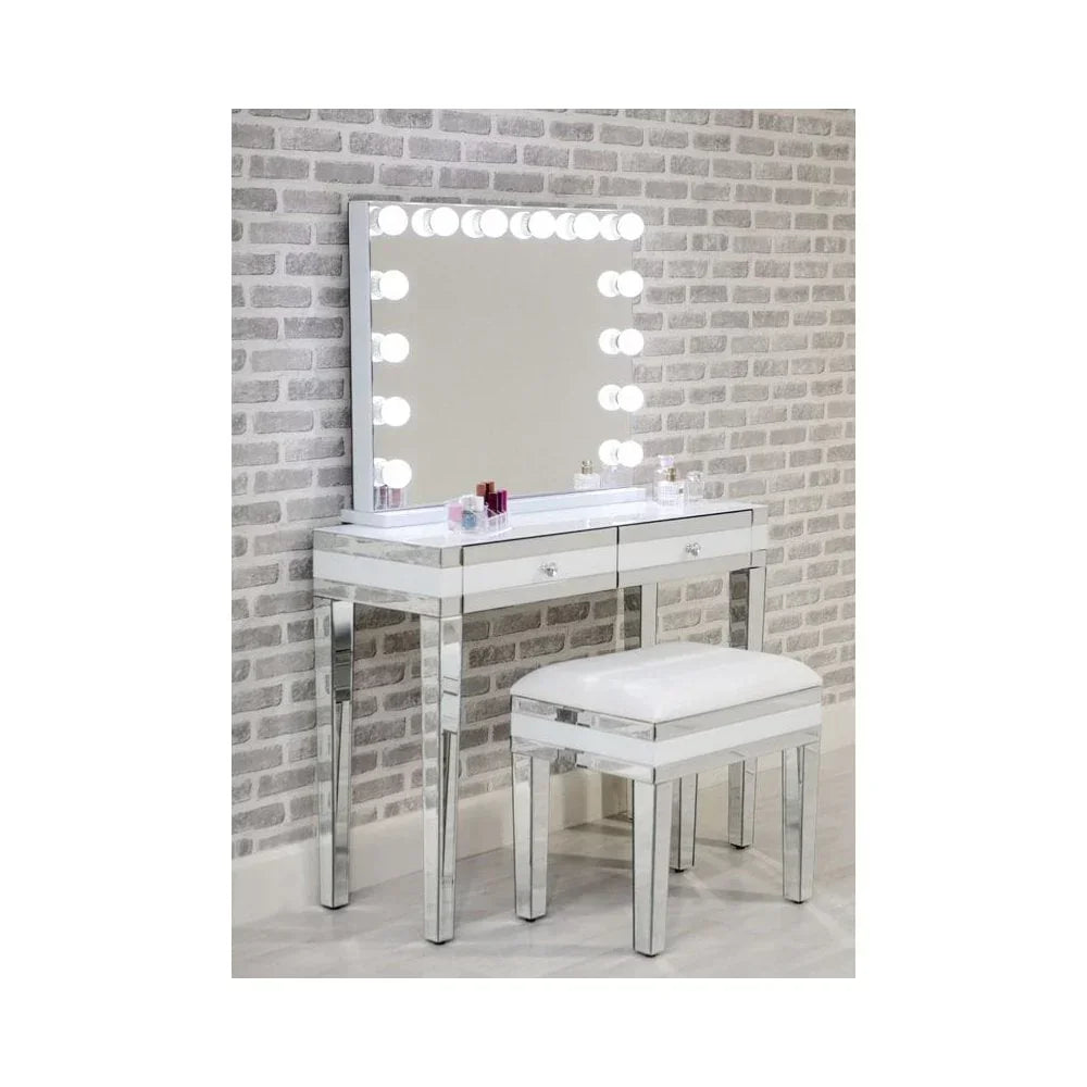 mirrored dressing table with Hollywood lighted mirror and padded stool against brick wall