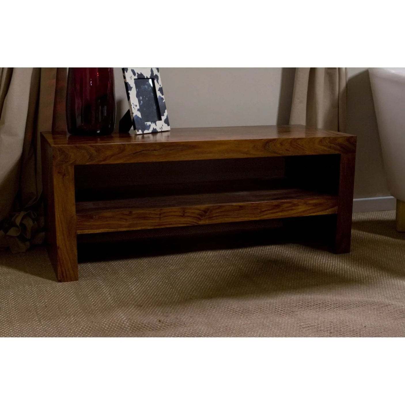 Solid wood coffee table with shelf in living room setting, decorative items on top