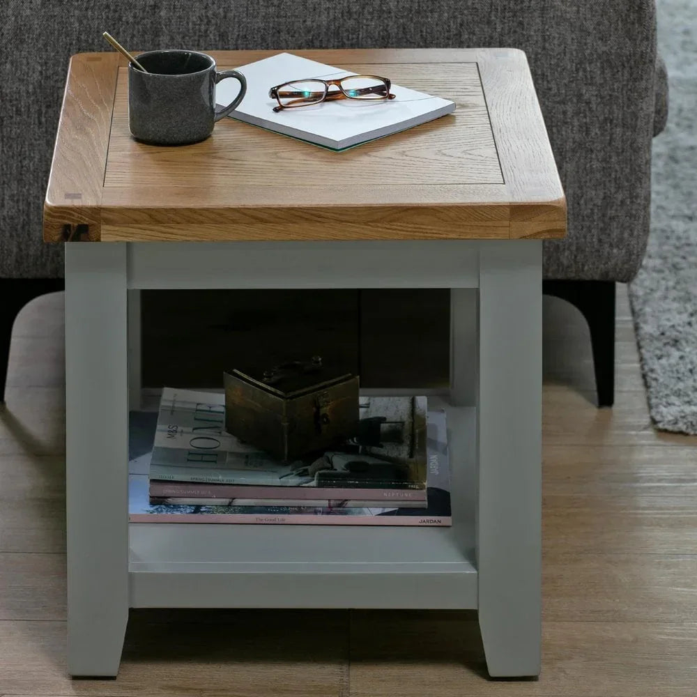 Oak and painted side table with cup, notebook, and glasses, lower shelf with books and box