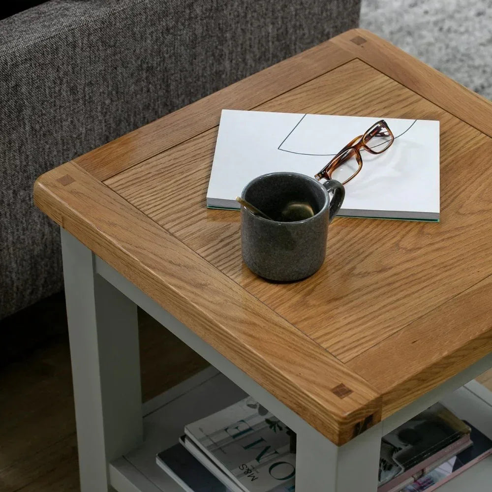 Oak and grey side table with mug, notebook, and glasses beside sofa