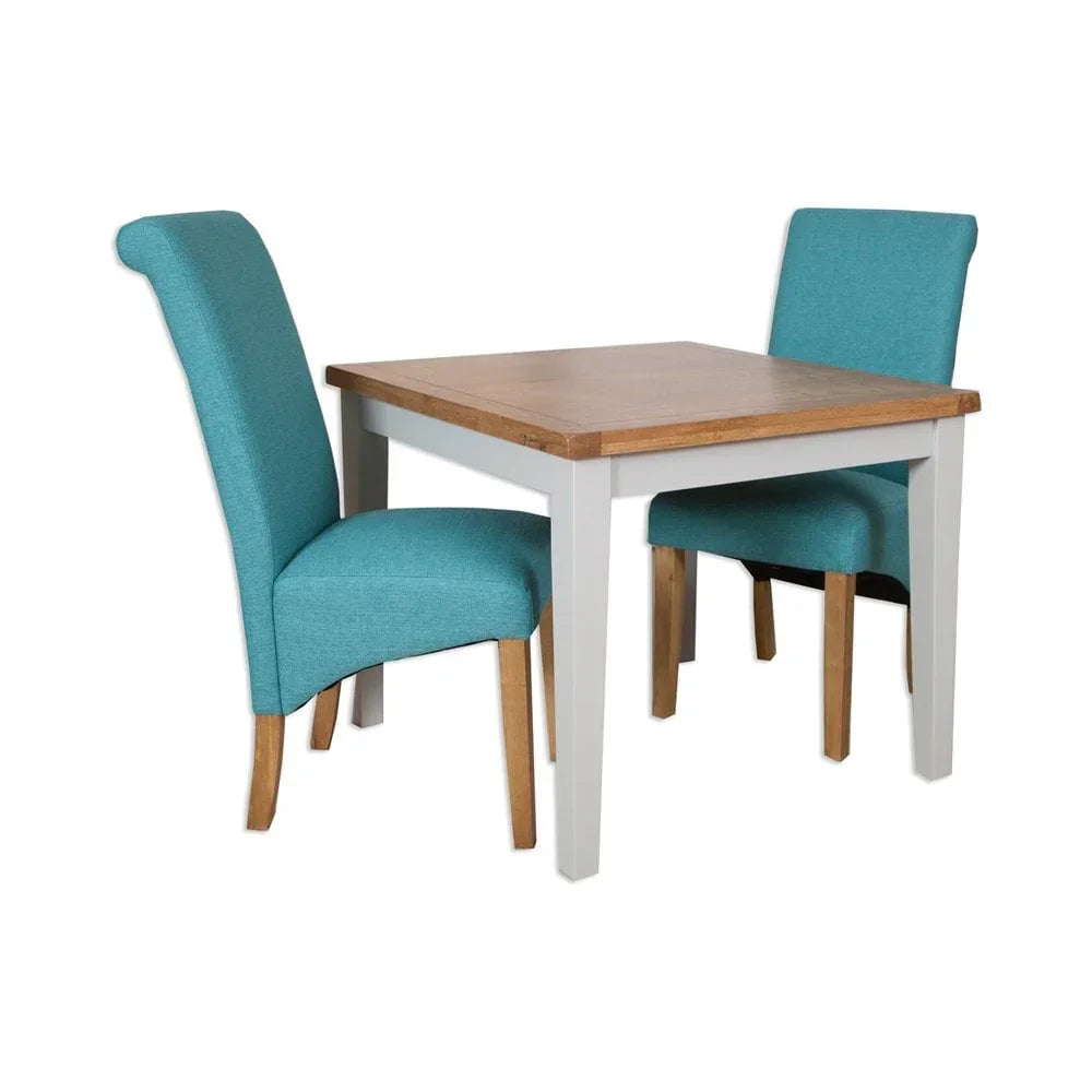 Wood dining table with white legs and two teal upholstered chairs