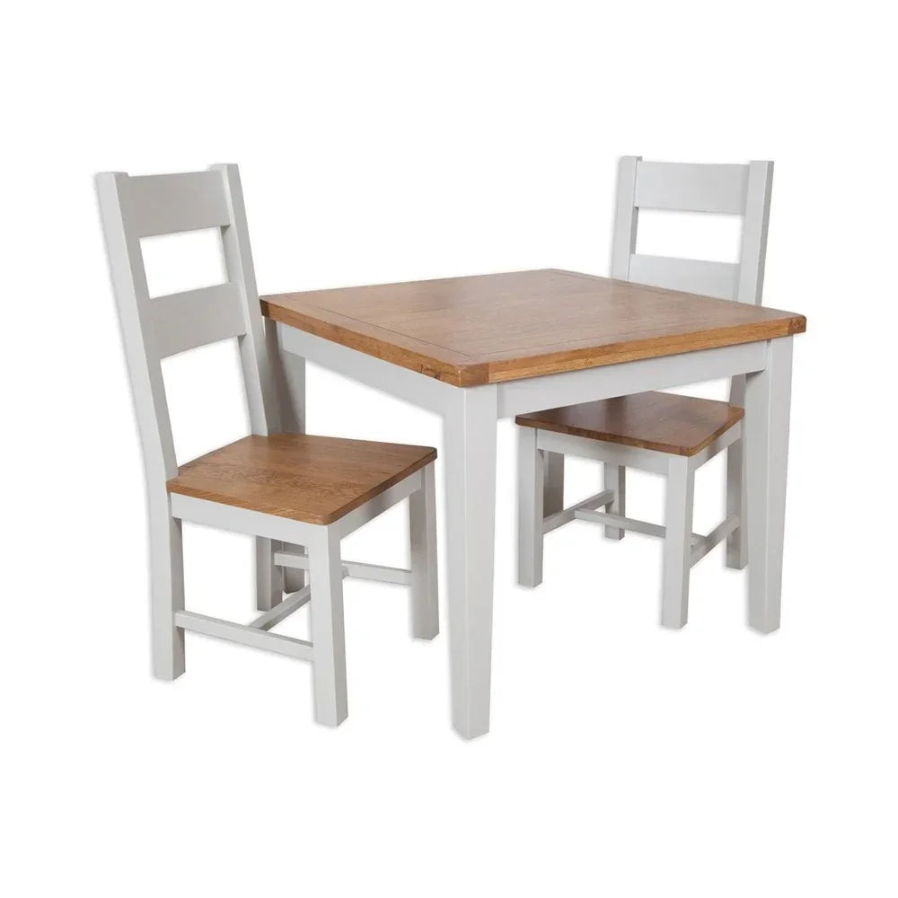 Wood dining table set with two white and oak chairs against a white background