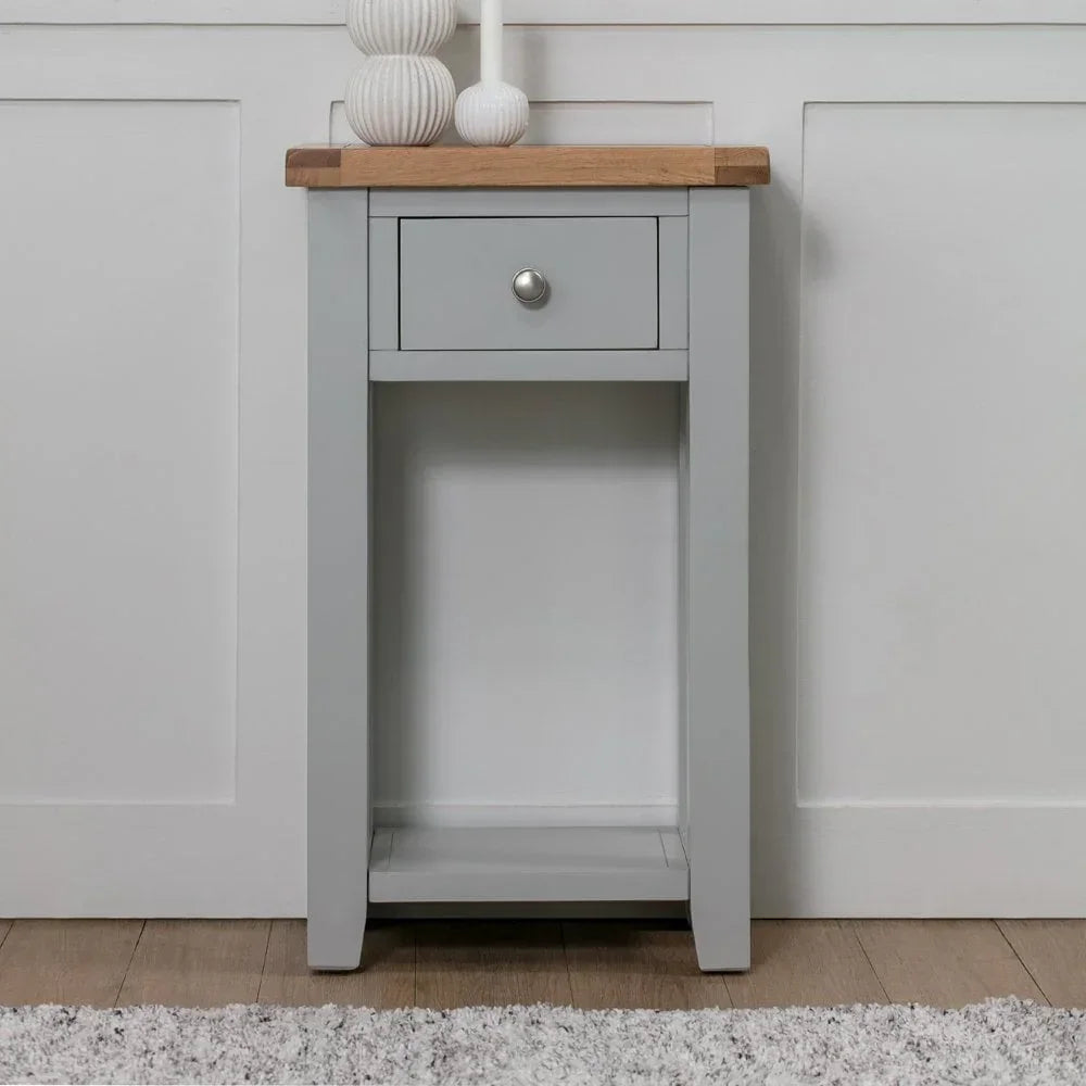 Grey painted narrow console table with oak top and single drawer against wall panel