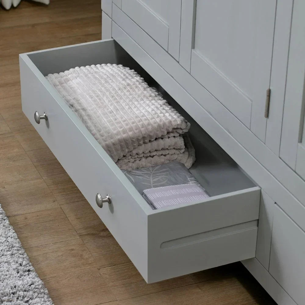 Grey wooden storage drawer with folded bedding and towels on wooden floor