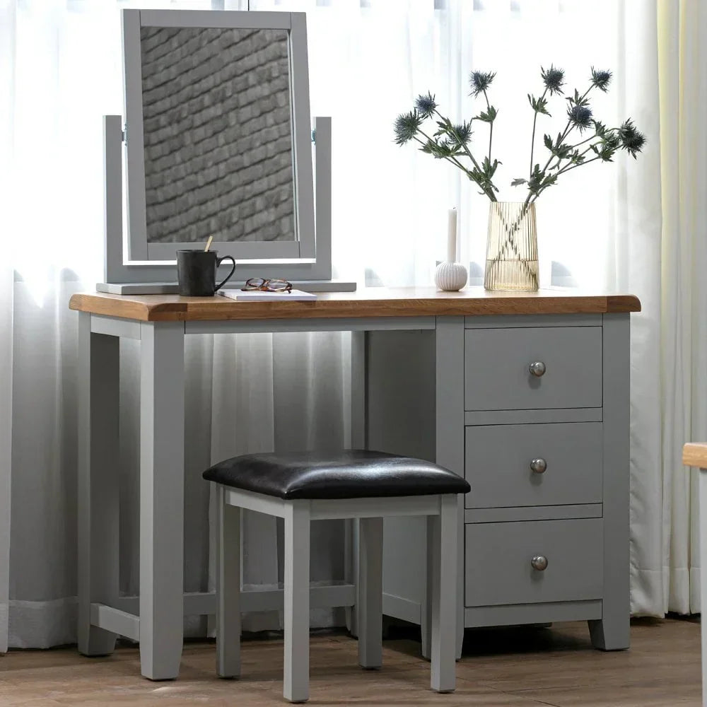 Grey dressing table with mirror, three drawers, stool, and wood top in bright room