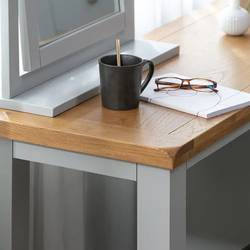 Light grey dressing table with oak top, black mug, notebook and glasses on surface