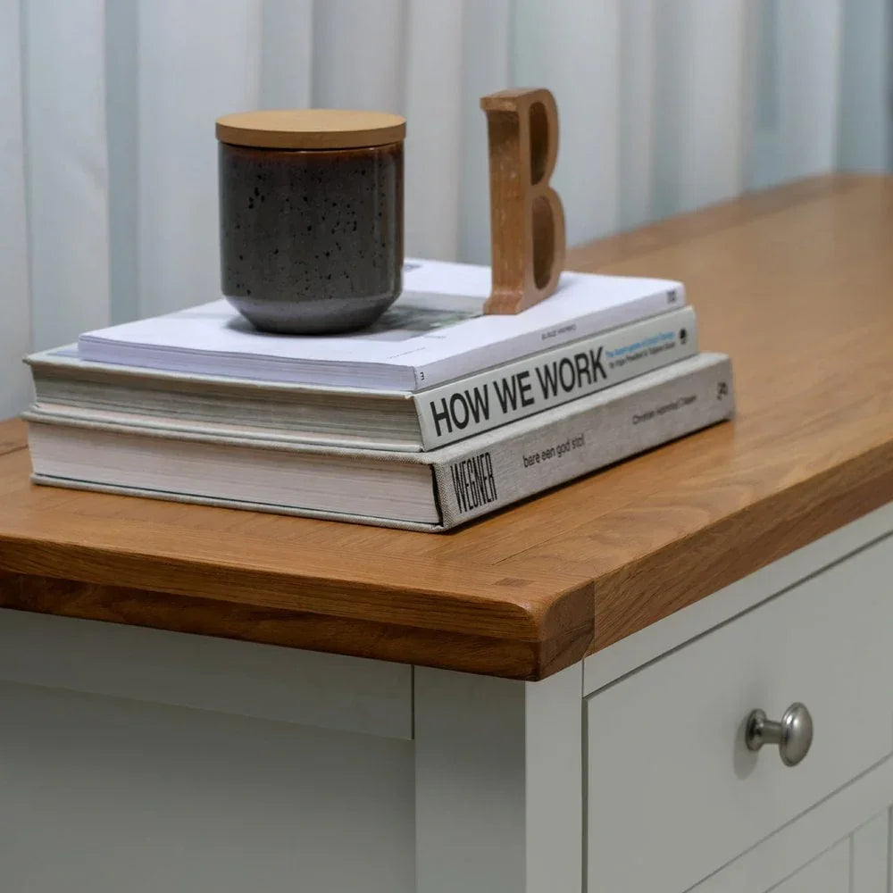 Oak top sideboard with grey drawer, books, and a ceramic jar for home storage