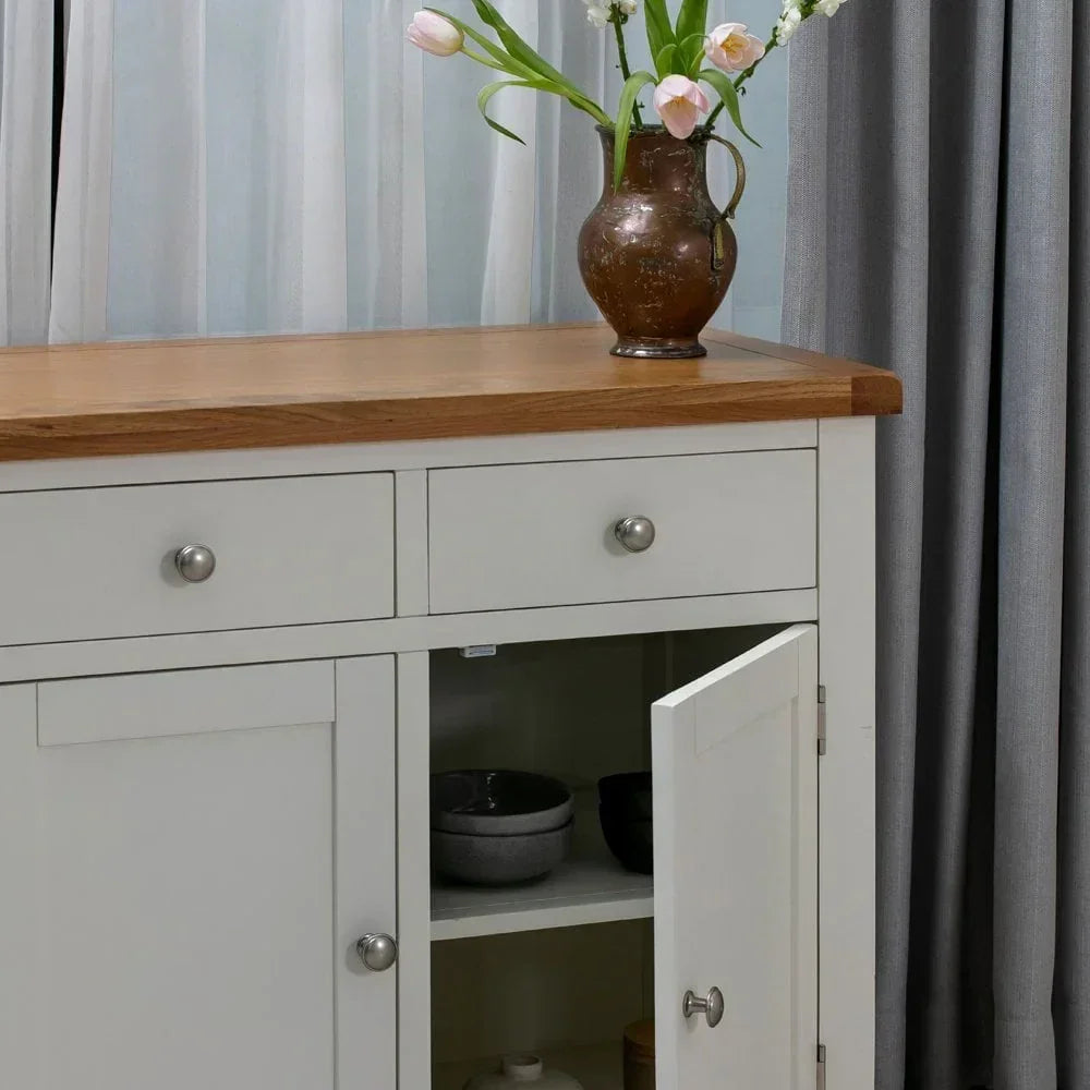 White sideboard with oak top, open cabinet door, and ceramic vase with flowers