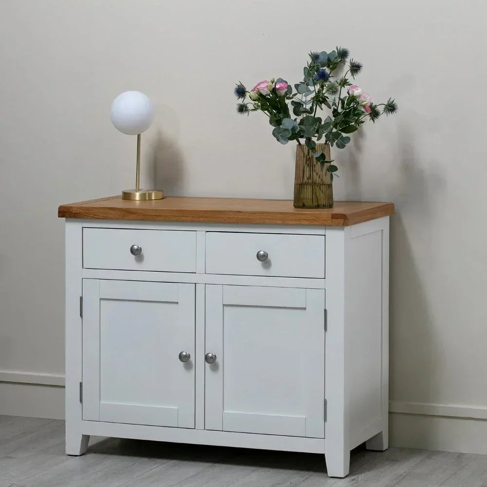 White sideboard with oak top, two drawers, and doors, styled with lamp and flowers