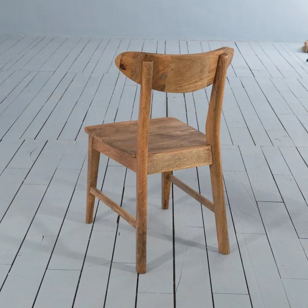 Solid wood dining chair with curved backrest on painted wooden floor